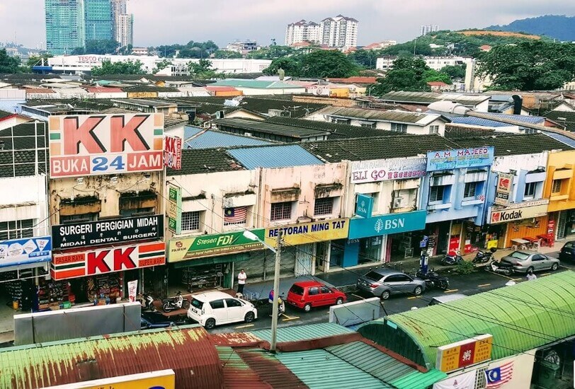Pemandangan dari atas deretan kedai yang menampilkan cawangan Bank Simpanan Nasional (BSN), kedai serbaneka KK Super Mart, Restoran Ming Tat, dan beberapa buah kenderaan di tepi jalan