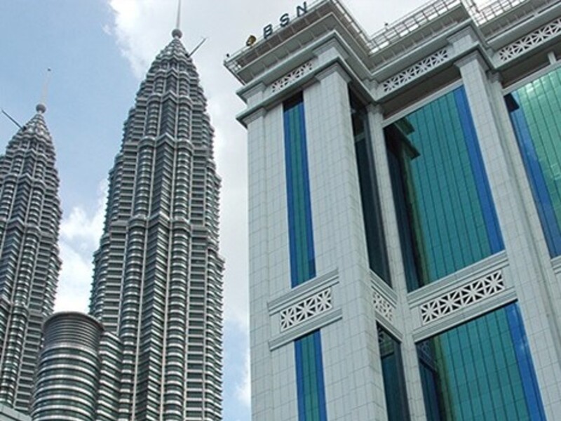Pandangan sudut rendah menunjukkan Menara Berkembar Petronas di sebelah kiri dan bangunan Bank Simpanan Nasional (BSN) yang mempunyai panel kaca hijau di sebelah kanan