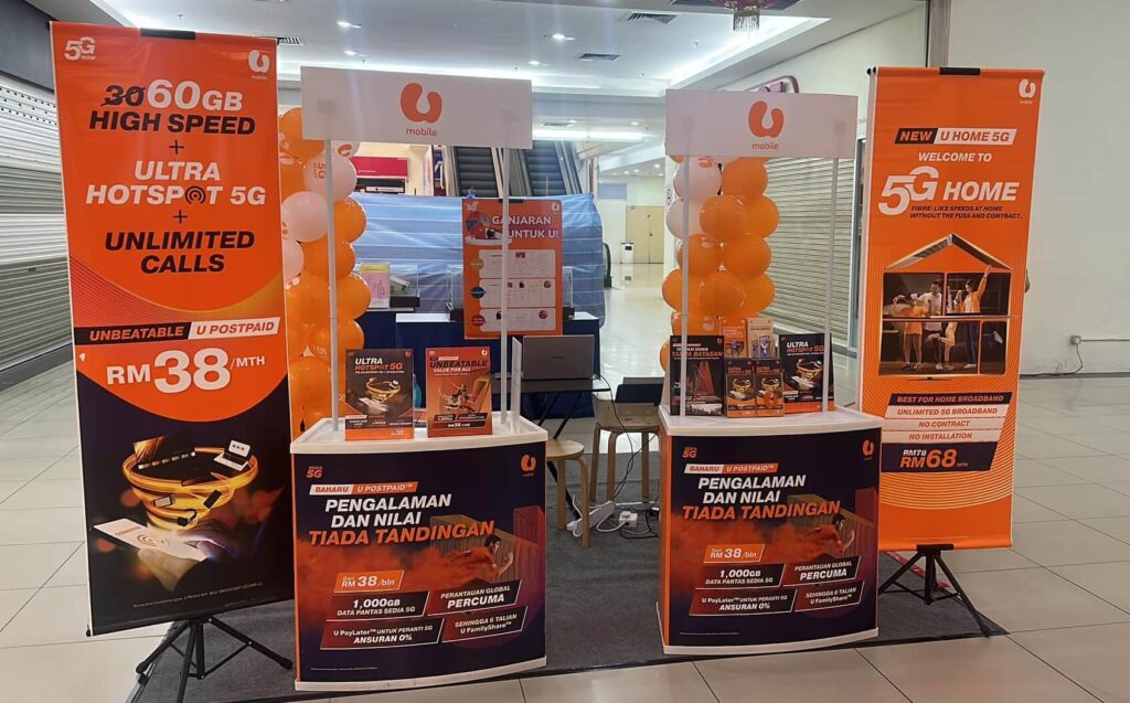 Imej menunjukkan gerai yang menawarkan pelbagai promosi dan maklumat perkhidmatan daripada U Mobile di U Mobile D garden Batu Pahat. Terdapat juga beberapa brosur yang biasanya diedarkan kepada pelanggan