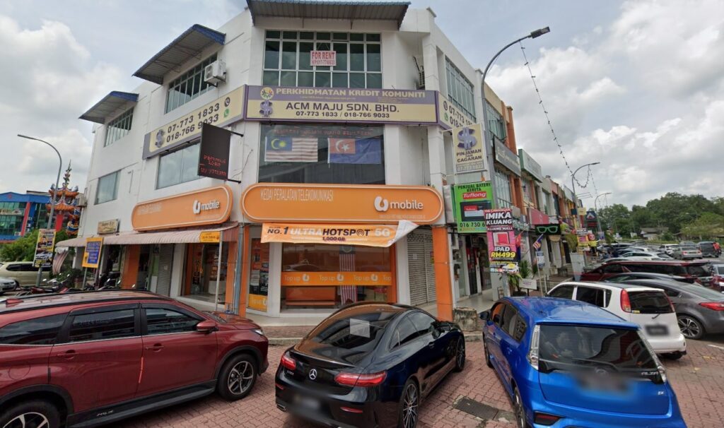 Lokasi U Mobile Kluang (Jalan Rambutan) - First Mobile World Sdn Bhd. Terletak di pinggir lebuh raya yang sibuk, terdapat banyak kereta yang parkir di sekitar lokasi. Dindingnya kebanyakannya berwarna oren dan terdapat papan tanda besar dengan logo dan tulisan U Mobile