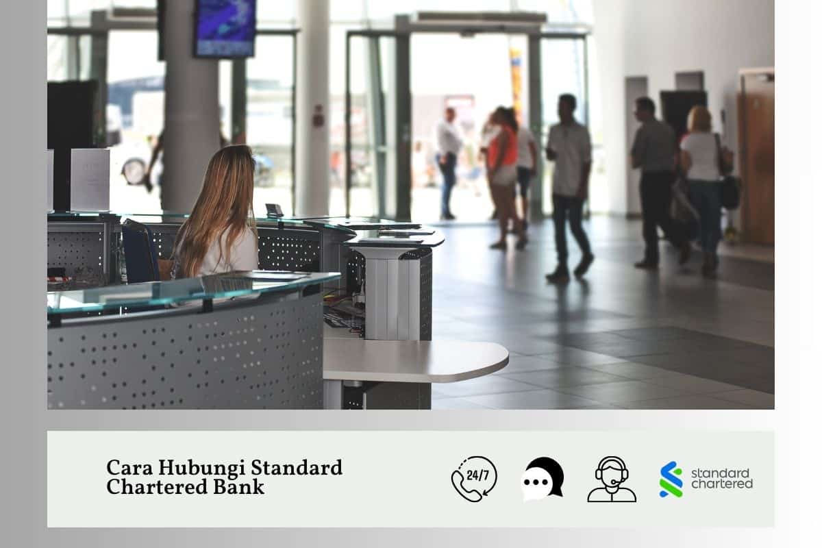 Lobi bank atau kawasan perkhidmatan pelanggan yang moden dan sibuk. Di latar depan, seorang wanita berambut perang panjang duduk di belakang meja perkhidmatan pelanggan atau penerimaan tetamu dengan panel hadapan logam berlubang yang tersendiri. Dia kelihatan bekerja atau menunggu pelanggan