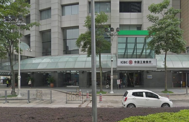 Pintu masuk aras jalan bangunan Industrial and Commercial Bank of China (Malaysia) Berhad Kuala Lumpur HQ di Kuala Lumpur. Fasad bangunan adalah bangunan pencakar langit moden berwarna terang. Kanopi kaca melengkung terbentang di kawasan pintu masuk utama