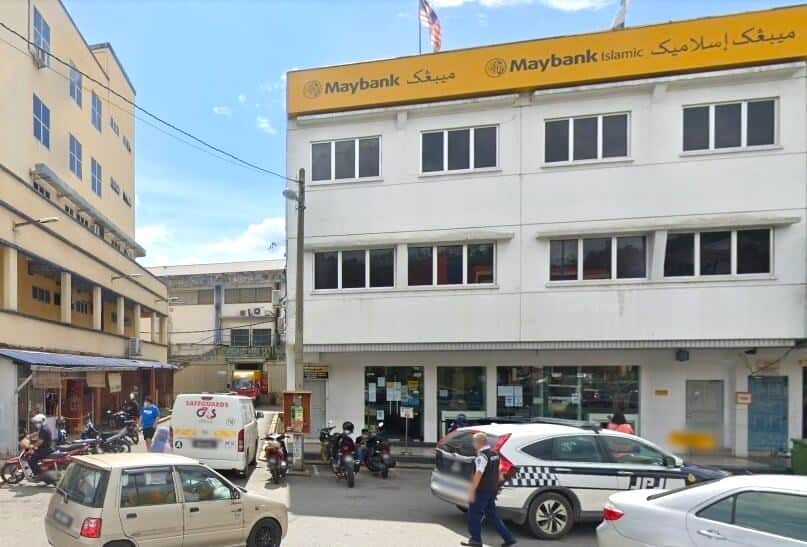 Gambar siang hari dari aras jalan menunjukkan cawangan Maybank Bentong di Malaysia. Bangunan itu adalah bangunan putih tiga tingkat dengan papan tanda kuning dan hitam yang memaparkan logo Maybank dan perkataan "Maybank Islamic." Tingkat bawah berlapis dengan pelekat, dan terdapat banyak kereta dan motosikal diletakkan di hadapan