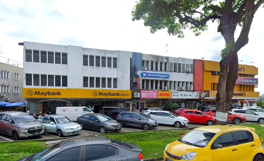 Gambar dari hadapan pejabat tiga tingkat Maybank Taman Pelangi dengan cat putih. Terdapat logo dan tulisan Maybank dan Maybank Islamic di hadapan