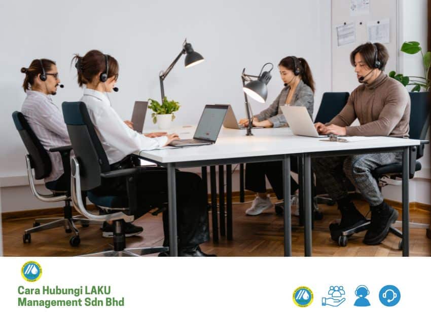 Empat wakil khidmat pelanggan memakai set kepala, duduk di meja putih dan bekerja pada komputer riba di pejabat