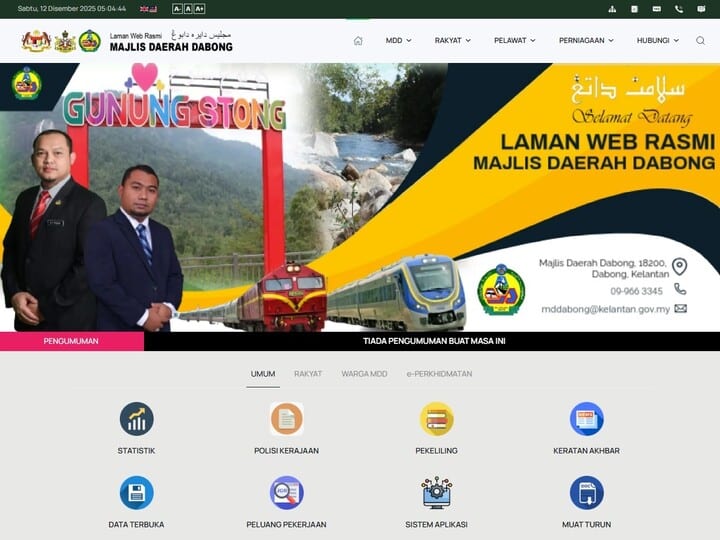 Tangkapan skrin laman web rasmi Majlis Daerah Dabong, menunjukkan imej tajuk dengan teks "SELAMAT DATANG KE LAMAN WEB RASMI MAJLIS DAERAH DABONG" dan imej dua lelaki berpakaian sut, papan tanda "GUNUNG STONG", sebuah sungai, dan dua kereta api, berserta menu navigasi dan ikon untuk perkhidmatan dan statistik jawatan kosong