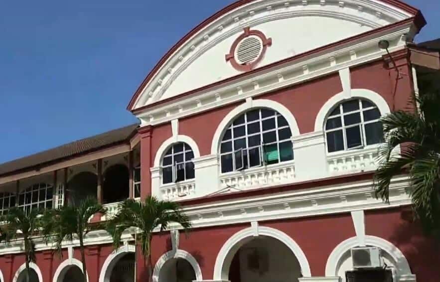 Bangunan bersejarah dua tingkat era kolonial dengan fasad merah dan putih, menampilkan tingkap melengkung besar di tingkat bawah dan dua