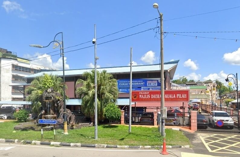 Bangunan Majlis Daerah Kuala Pilah. Pintu masuk mempunyai papan tanda merah putih yang tertera nama majlis dalam bahasa Melayu. Di latar depan terdapat air pancut kecil yang dikelilingi oleh pokok palma, dan bangunan itu sendiri mempunyai bumbung berhias biru