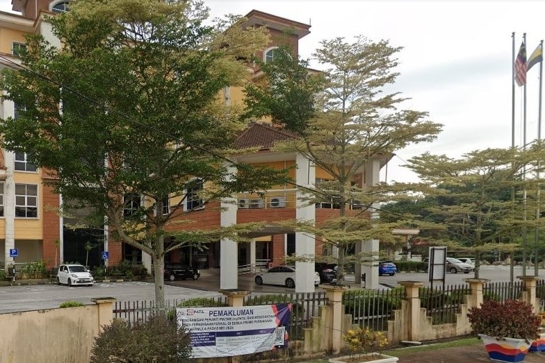 Gambar menunjukkan bahagian hadapan pejabat Majlis Daerah Tanjong Malim pada sebelah petang. Bangunan tinggi itu mempunyai halaman yang luas sebagai kawasan parkir. Pagar diperbuat daripada konkrit dan teralis besi. Di bahagian hadapan juga terdapat sepanduk pengumuman daripada MDTM