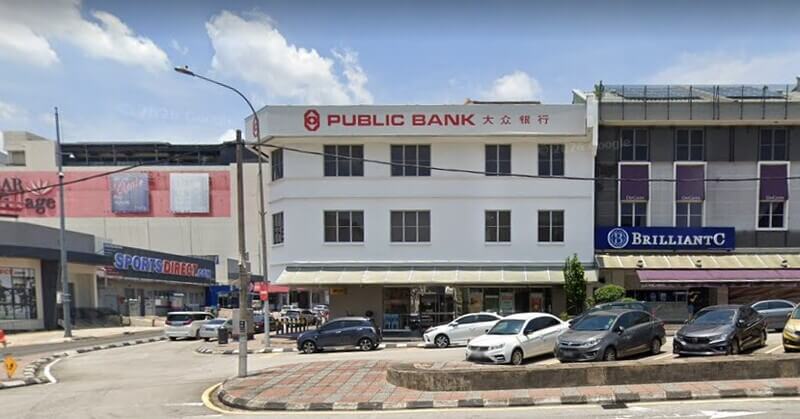 Bangunan cawangan Public Bank Bangsar tiga tingkat berwarna putih dengan beberapa buah kereta diletakkan di hadapannya di kawasan kedai.