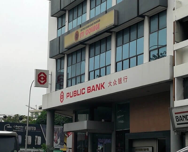 Pemandangan dari sudut tepi bangunan cawangan Public Bank Jalan Ipoh dengan papan tanda "PUBLIC BANK 大众银行" dan logo teksi/kolej STI College di tingkat atas.