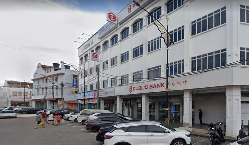 Pandangan luaran bangunan cawangan Public Bank di Kluang dengan tempat meletak kenderaan di hadapannya.