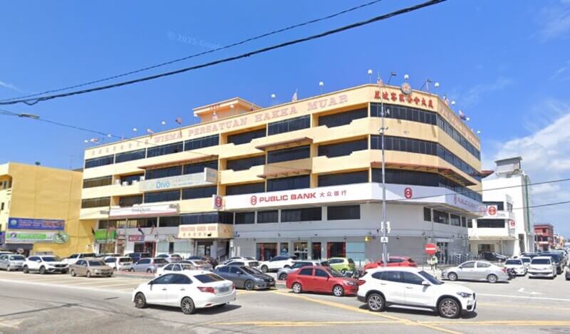 Pandangan luaran bangunan Wisma Persatuan Hakka Muar yang menempatkan cawangan Public Bank Muar di tingkat bawah di tepi jalan yang sibuk.