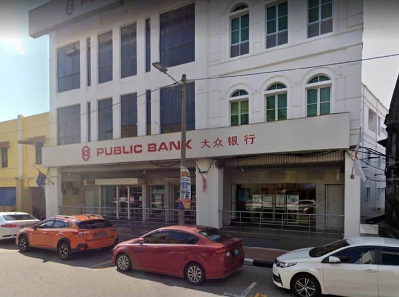Foto bangunan Public Bank Jalan Abdullah tiga tingkat berwarna terang. Bangunan ini mempunyai beberapa tingkap melengkung dan segi empat tepat. Papan tanda besar yang tertera nama bank dalam bahasa Inggeris dan Mandarin kelihatan di tingkat dua