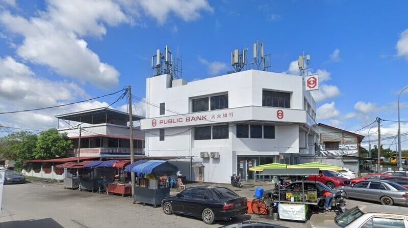 Bangunan Public Bank di Changlun dengan gerai penjaja dan kereta di hadapannya memaparkan papan tanda bank, menara pemancar di atas bumbung, serta kenderaan yang diletakkan di kawasan sekeliling