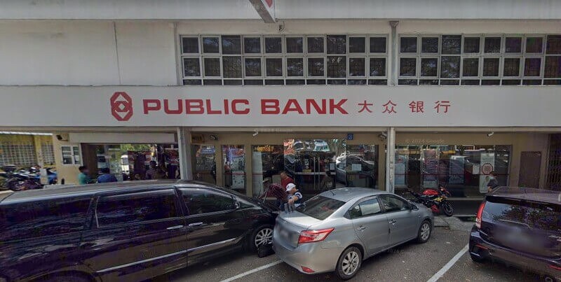 Pandangan hadapan cawangan Public Bank Kulai dengan papan tanda merah dan tulisan Cina, serta beberapa buah kereta diletakkan di tempat letak kereta di hadapan premis. Sc: Google Street View & 360.