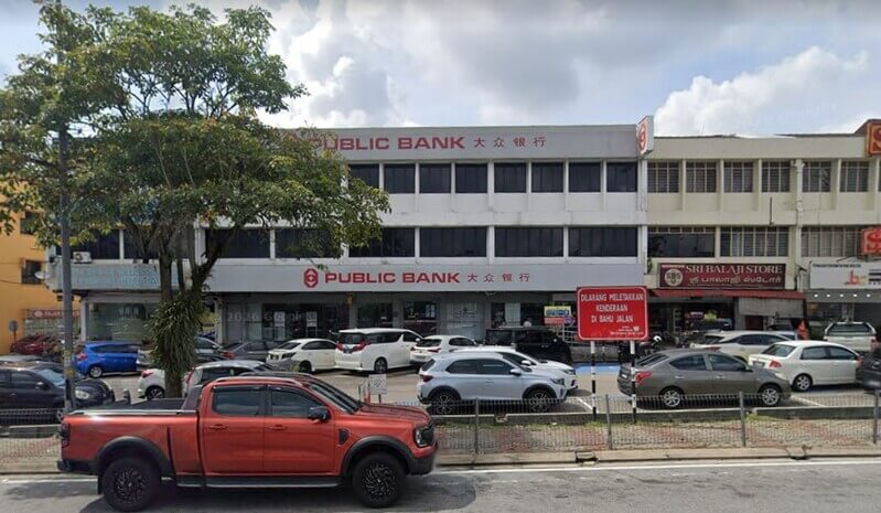 Pandangan hadapan bangunan cawangan Public Bank Taman Perling tiga tingkat dengan papan tanda 'PUBLIC BANK 大众银行' dan kawasan tempat meletak kereta di hadapannya.