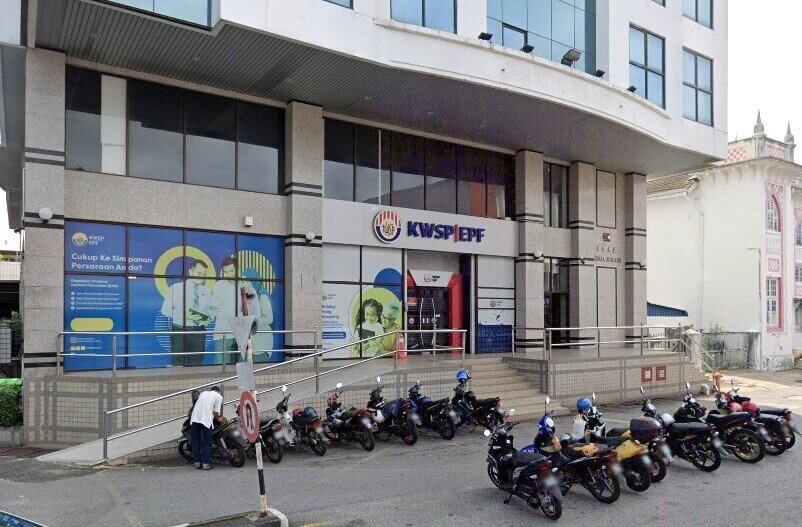 Gambar siang hari dari jalan bangunan pejabat KWSP (EPF) di Sungai Petani, Malaysia. Bangunan berbilang tingkat ini menampilkan reka bentuk moden yang minimalis dengan tingkap kaca besar di tingkat atas dan pintu masuk utama. Logo KWSP|EPF terpampang jelas di atas pintu masuk.