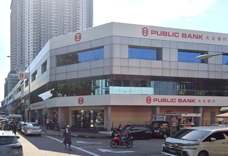 Bahagian luar bangunan cawangan Public Bank, boleh dikenali dengan logo merah yang menyerlah dan teks "PUBLIC BANK" bersama-sama dengan nama Cinanya pada muka depannya yang putih dan kelabu. Bangunan ini adalah struktur moden tiga tingkat dengan tingkap biru reflektif yang besar di tingkat atas