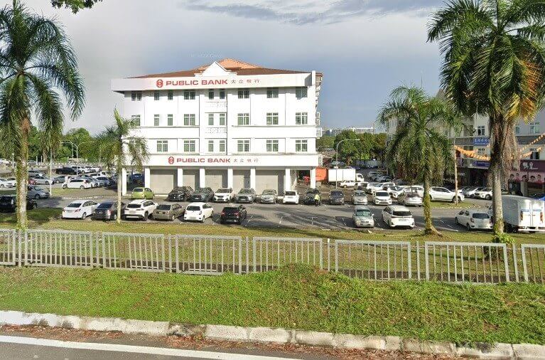 Bahagian luar bangunan cawangan Public Bank Stutong, bangunan bertingkat berwarna putih berbumbung merah, terletak di kawasan komersial dengan kawasan parkir yang luas dan sebahagiannya diduduki di hadapannya
