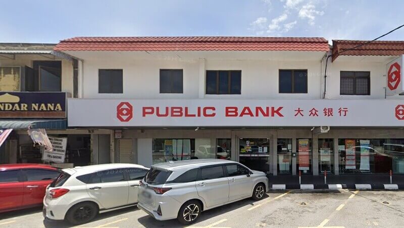 Pemandangan hadapan cawangan Public Bank Bandar Bayan Baru di kawasan kedai dua tingkat dengan beberapa buah kereta diletakkan di tempat letak kereta di hadapannya.