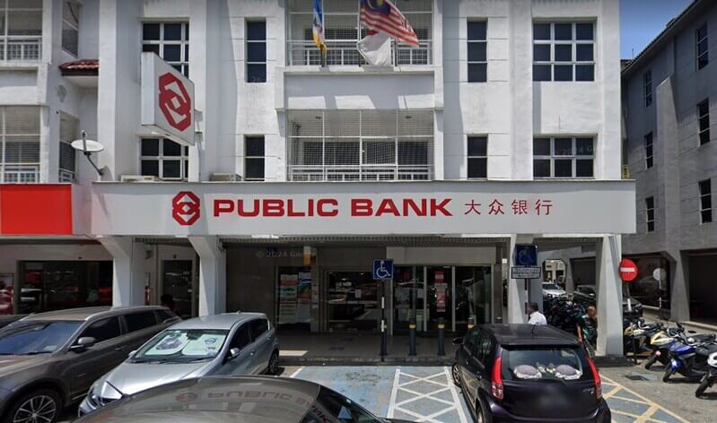 Pandangan hadapan bangunan cawangan Public Bank di Seberang Jaya dengan papan tanda bank, tempat letak kereta, dan beberapa kenderaan di hadapannya.