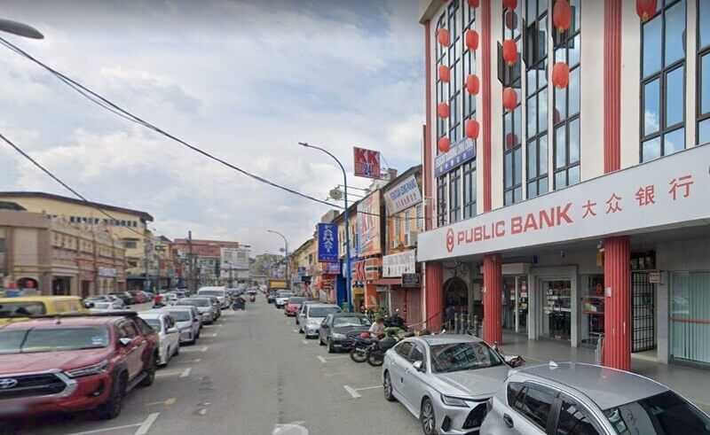 Pandangan jalan raya di kawasan bandar yang menampilkan bangunan cawanganPublic Bank Bentong di sebelah kanan serta kenderaan yang diletakkan di sepanjang bahu jalan.