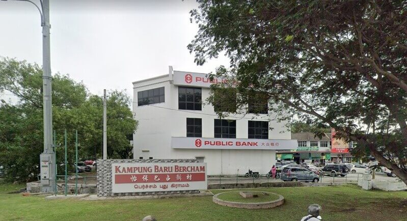 Bangunan cawangan Public Bank Bercham tiga tingkat berwarna putih dengan papan tanda "Kampung Baru Bercham" di bahagian hadapan di tepi jalan.