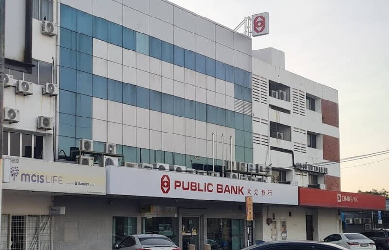 Pandangan hadapan bangunan cawangan Public Bank di Butterworth dengan papan tanda "PUBLIC BANK" dan logo merah, berserta premis bersebelahan seperti MCIS Life dan CIMB Bank.