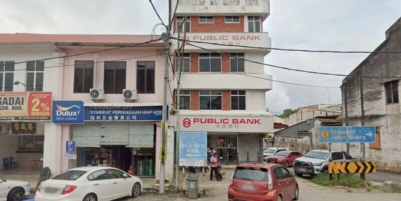 Bangunan kedai empat tingkat cawangan Public Bank di Gemas dengan papan tanda jalan di hadapannya dan kedai cat Dulux di sebelah kiri.