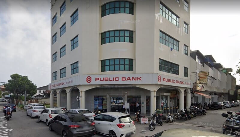 Pandangan luar bangunan cawangan Public Bank Jalan Datuk Keramat di sudut jalan dengan kereta dan motosikal diletakkan di hadapan.