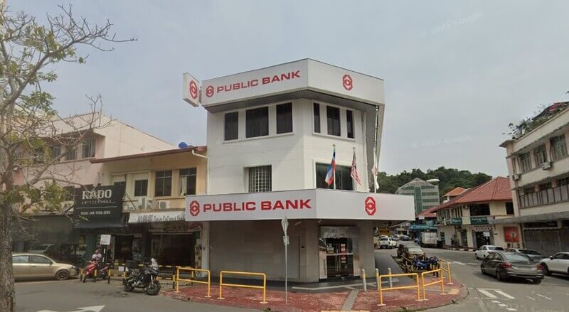 Bangunan Public Bank Jalan Pantai berwarna putih di kawasan bandar, dengan papan tanda “PUBLIC BANK” pada bahagian hadapan. Beberapa bendera dipasang di hadapan bangunan.