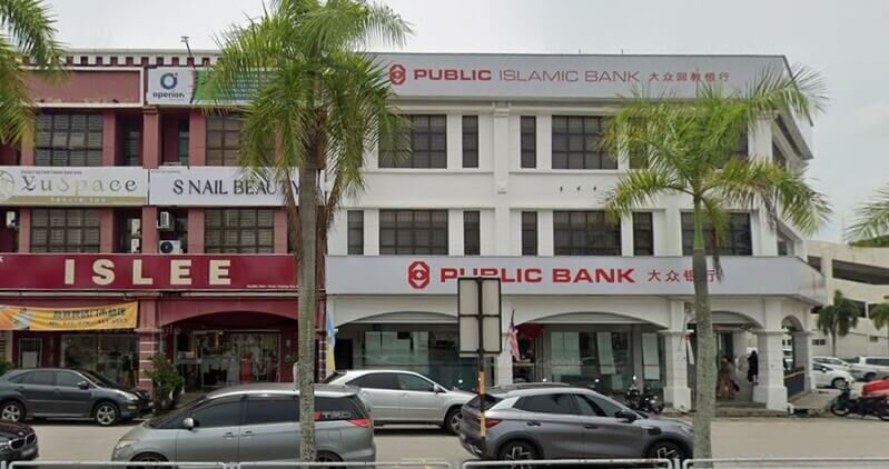 Bangunan Public Bank Jalan Raja Uda dan Public Islamic Bank tiga tingkat di tepi jalan dengan deretan kereta diletakkan di hadapannya.