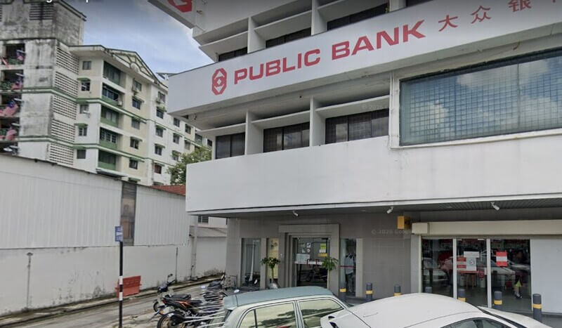 Pemandangan luar bangunan cawangan Public Bank Jelutong dengan tulisan papan tanda Public Bank dan kepingan kaca di bahagian hadapan.