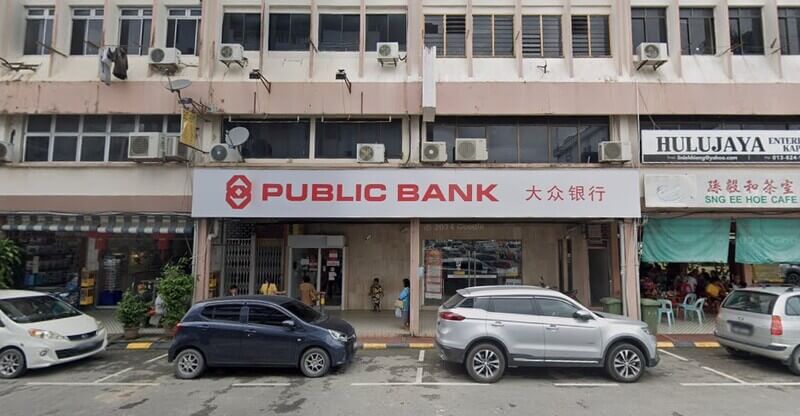 Pandangan hadapan cawangan Public Bank di Kapit di sebuah bangunan kedai tiga tingkat dengan beberapa buah kereta diletakkan di tempat letak kereta di bahagian hadapan.