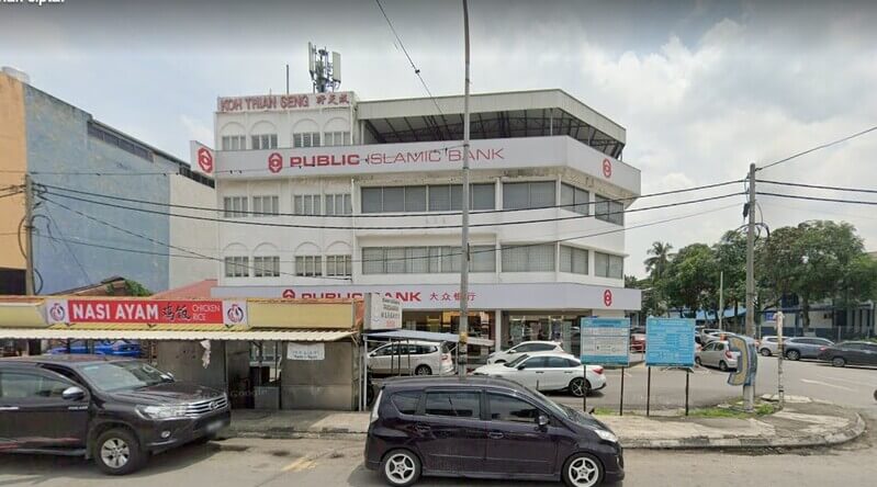 Bangunan cawangan Public Bank Pandamaran dan Public Islamic Bank bertingkat di tepi jalan dengan gerai nasi ayam di bahagian hadapan.