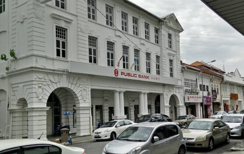 Pemandangan luar bangunan warisan Public Bank cawangan Pulau Pinang berwarna putih dengan beberapa buah kereta diletakkan di hadapannya.