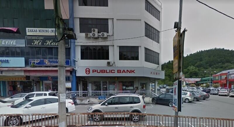 Pemandangan depan cawangan Public Bank Raub di sebuah bangunan kedai bertingkat dengan deretan kereta diletakkan di bahagian hadapan.