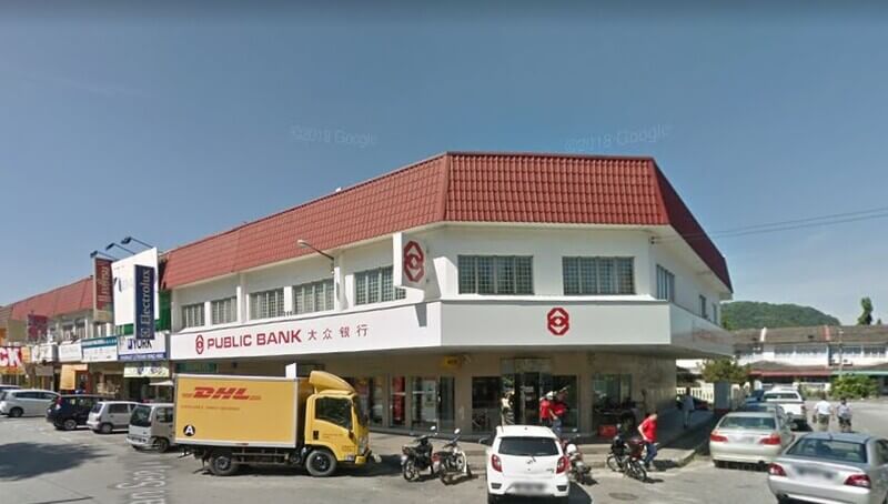 Pemandangan luar cawangan Public Bank Simpang Pulai dua tingkat di lot kedai sudut dengan trak DHL dan beberapa kenderaan diletakkan di hadapannya.
