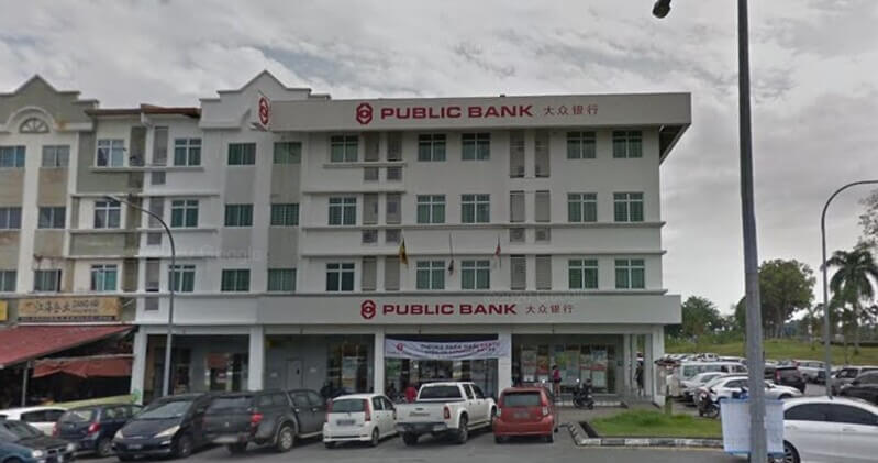 Pandangan hadapan bangunan cawangan Public Bank Stutong empat tingkat dengan papan tanda nama bank serta kenderaan yang diletakkan di bahagian hadapan.