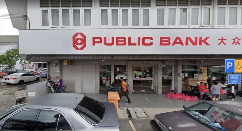 Pandangan hadapan cawangan Public Bank Taman Chi Liung dengan papan tanda merah dan putih, menunjukkan pintu masuk premis serta kenderaan yang diletakkan di bahagian hadapan.