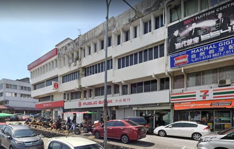 Pandangan luar bangunan kedai tiga tingkat yang menempatkan cawangan Public Bank Taman Connaught dan kedai 7-Eleven di tingkat bawah, dengan kenderaan diletakkan di sepanjang jalan di hadapannya.