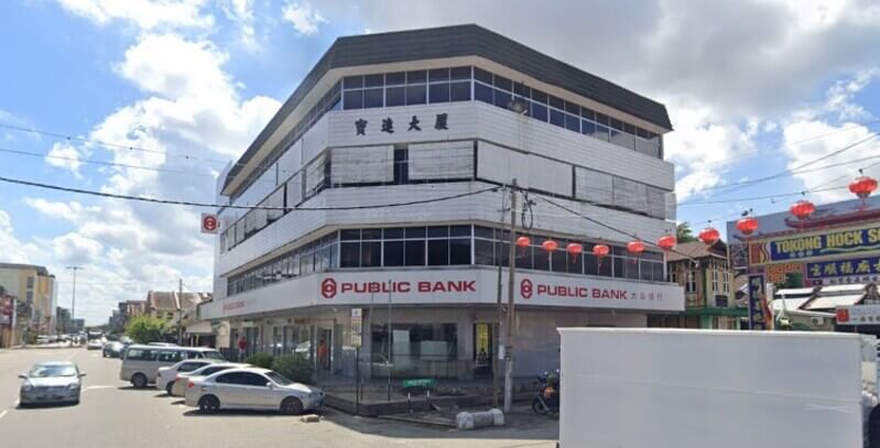 Bangunan cawangan Public Bank Teluk Intan tiga tingkat di persimpangan jalan dengan tanglung cina bergantung di sebelah kanan.