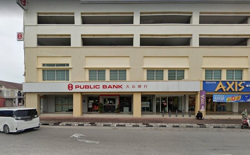 Bangunan cawangan Public Bank Tengkera dengan papan tanda bercetak tulisan merah dalam bahasa Inggeris dan Cina, bersebelahan kedai cermin mata AXIS.