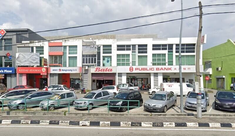 Pandangan luar barisan kedai di tepi jalan yang menempatkan cawangan Public Bank Gunung Rapat, Bata, Hong Leong Bank, Kedai Ayamas, dan Domino's Pizza bersama deretan kereta di petak letak kenderaan.