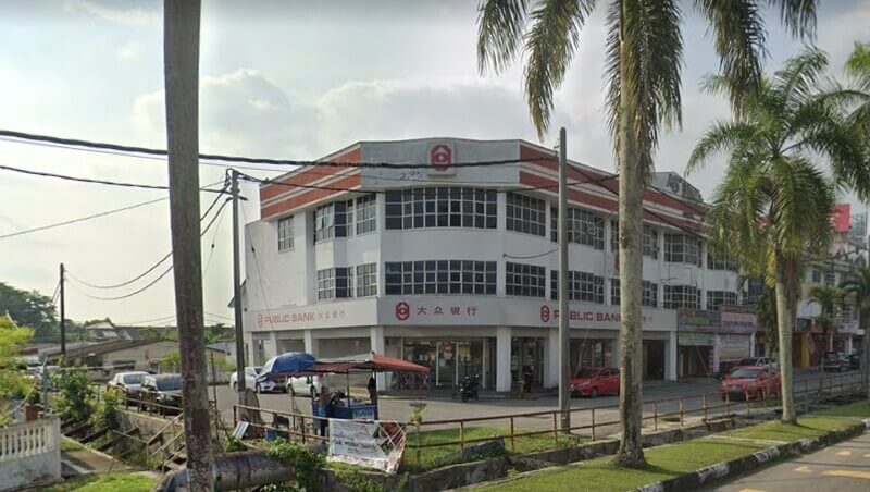 Pandangan luar bangunan cawangan Public Bank di Kamunting dengan papan tanda bank, pokok kelapa sawit/pinnate, dan jalan raya di hadapannya.