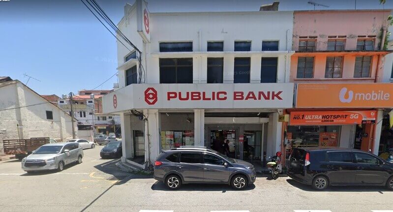 Pandangan hadapan cawangan Public Bank Kuala Kangsar dan kedai U Mobile di bangunan kedai dua tingkat dengan kereta diletakkan di luar.
