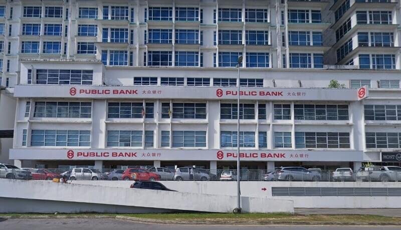 Bangunan cawangan Public Bank Bintulu berwarna putih dengan papan tanda bercetak papan nama "PUBLIC BANK" dan tulisan Cina, serta deretan kereta yang diletakkan di bahagian hadapan.
