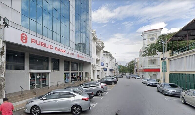 Pemandangan luar bangunan cawangan utama Public Bank Ipoh Main Office di tepi jalan raya dengan kereta diletakkan di petak letak kereta.