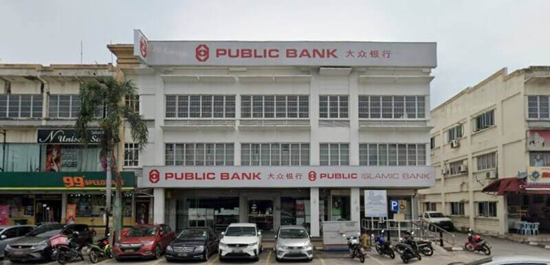 Pandangan hadapan bangunan cawangan Public Bank Kapar dan Public Islamic Bank bertingkat putih dengan deretan kereta yang diletakkan di bahagian hadapan.